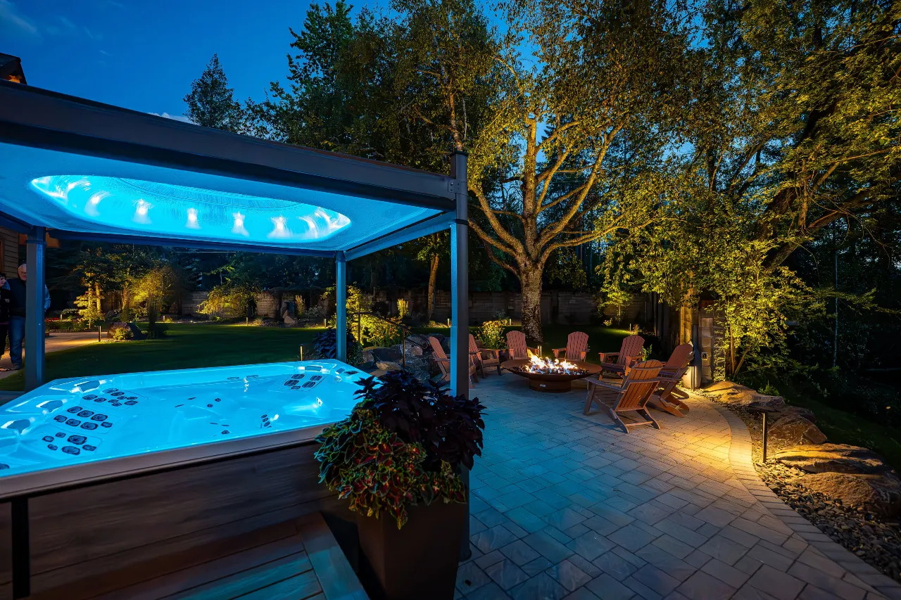 Representative Legacy Landscapes portfolio: elevated view of a landscaped backyard with a pool, covered poolside structure, patio seating, trees, and landscape lighting.